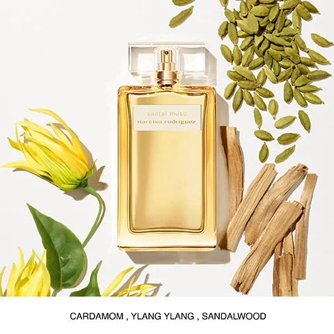 A perfume bottle labeled santal musc by narciso rodriguez is surrounded by yellow flowers, cardamom pods, and pieces of wood, with the words CARDAMOM, YLANG YLANG, SANDALWOOD displayed below.