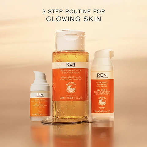Image 1 - Three skincare products arranged on a surface, featuring a bottle of REN Ready Steady Glow Daily AHA Tonic, a tube of Brightening Dark Circle Eye Cream, and a pump bottle of Glow Daily Vitamin C Gel Cream, with the text 3 STEP ROUTINE FOR GLOWING SKIN displayed above.
Image 2 - A bottle of REN Ready Steady Glow Daily AHA Tonic with an orange label sits on a surface, with the text above stating STEP 1 EXFOLIATE DEAD SKIN + CLOGGED PORES.
Image 3 - A skincare product bottle labeled REN Clean Skincare Glow Daily Vitamin C Gel Cream with visible text stating STEP 2 HYDRATE + EVEN SKIN TONE and the creams volume is 50 ml / 1.7 fl oz U.S.
Image 4 - A skincare product bottle for REN Clean Skincares Brightening Dark Circle Eye Cream is displayed with a blurred neutral background, featuring the text STEP 3 BRIGHTEN DARK CIRCLES + DEPUFF.