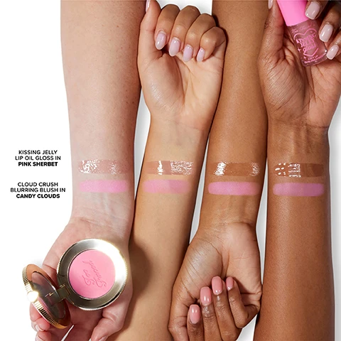 Image 1 - Four forearms with varying skin tones display swatches of a glossy clear-pink Kissing Jelly Lip Oil Gloss in Pink Sherbet and a matte light-pink Cloud Crush Blurring Blush in Candy Clouds, with a gold Too Faced blush compact held in the bottom left and a pink Too Faced Kissing Jelly Lip Oil Gloss bottle held in the top right. Image 2 - The image displays a pink blush compact with scattered powder and a swatch, labeled Cloud Crush Blurring Blush in Candy Clouds, alongside a pink lip oil gloss tube and swatch, labeled Kissing Jelly Lip Oil Gloss in Pink Sherbet, with two different models showcasing the blush and gloss.